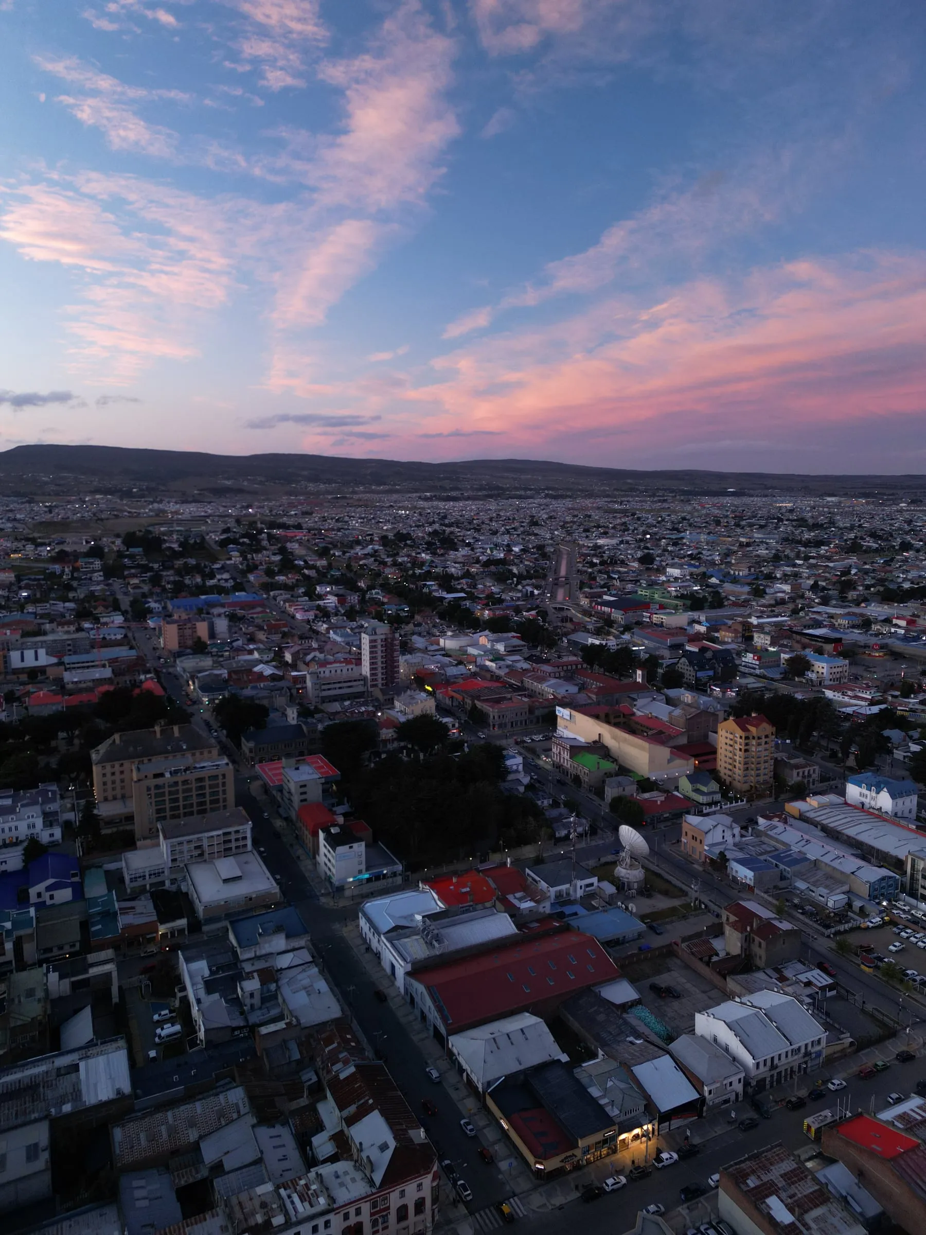 Punta Arenas vista desde el aire al atardecer, con el cielo teñido de rosa